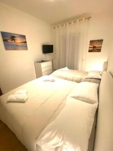 a white bedroom with two beds and a television at HomeClass in Bari