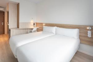 a large white bed in a hotel room at B&B HOTEL Lisboa Oeiras in Oeiras