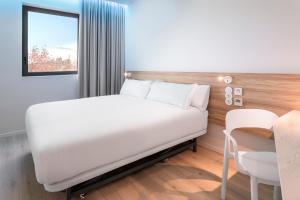 1 dormitorio con cama blanca y mesa en B&B HOTEL Lisboa Oeiras en Oeiras
