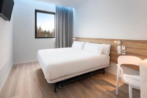 a bedroom with a white bed and a table at B&B HOTEL Lisboa Oeiras in Oeiras