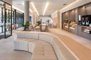 a lobby with a white bench in a building at B&B HOTEL Lisboa Oeiras in Oeiras