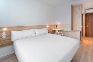 1 dormitorio con 1 cama blanca grande y escritorio en B&B HOTEL Lisboa Oeiras en Oeiras