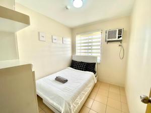 a small room with a bed and a window at 2BR condo within the city! w/ Pool, WIFI & Netflix in Davao City