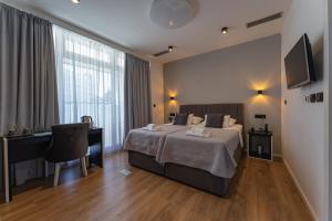 een slaapkamer met een bed, een bureau en een televisie bij Sky & Sun Luxury Rooms with private parking in the garage in Zadar