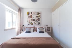 um quarto branco com uma cama grande e 2 almofadas em Lisbon Waves Surf Lodge em Costa da Caparica