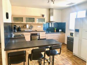 una cocina grande con mesa y sillas. en Villa de plein pied 120m2, climatisée, 3 chambres, piscine privée, la campagne aux portes de NARBONNE en Narbona