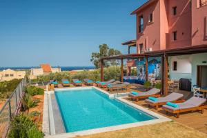 een buitenzwembad met ligstoelen en een huis bij Villa Greco in Chersonissos