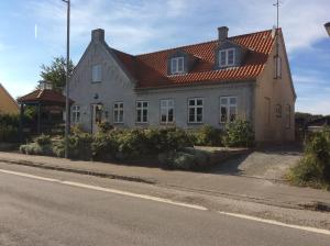 una casa con techo rojo al lado de una calle en Postholderens sted en Guldborg