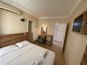 a bedroom with a bed and a desk and a television at Vesta Apart Hotel in Kuşadası