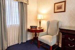 a room with a chair and a table and a lamp at Red Coach Inn in Niagara Falls