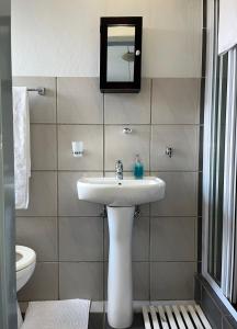 a bathroom with a sink and a mirror on the wall at Centurion Fully furnished lock up&go 1 bedroom apartment in Centurion