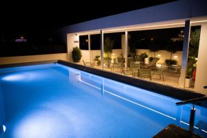 nQn Aparts & Suites Sevilla في إشبيلية: مسبح في الليل مع طاولة وكراسي