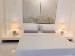 a bedroom with a white bed with two lamps at Saffron Robes Living in Hikkaduwa
