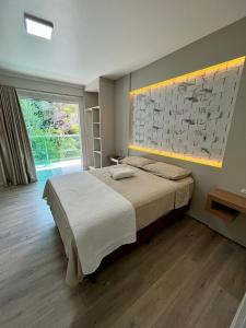 a bedroom with a large bed and a large window at Sítio novo pousada in Piratuba