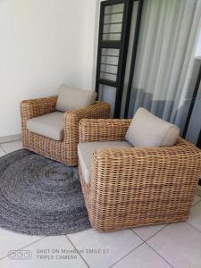 twee rieten stoelen en een poef in een kamer bij The Blyde Riverwalk Estate in Pretoria