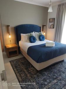 Schlafzimmer mit einem Bett mit blauer Bettwäsche und Kissen in der Unterkunft The Blyde Riverwalk Estate in Pretoria