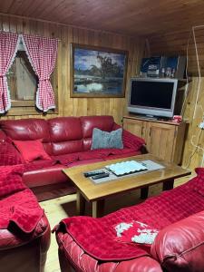 ein Wohnzimmer mit einem roten Ledersofa und einem Tisch in der Unterkunft Golija Vikendica Česta Vrela in Raška