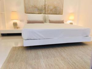 a white bed in a bedroom with two lamps and a rug at Saffron Robes Living in Hikkaduwa