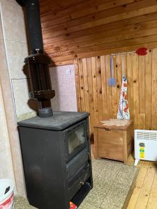 a black stove in a room with a wooden wall at Golija Vikendica Česta Vrela in Raška