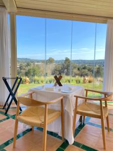 ein Esszimmer mit einem Tisch und Stühlen sowie einem großen Fenster in der Unterkunft La Almoraima Hotel in Castellar de la Frontera