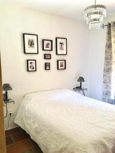 1 dormitorio con cama blanca y cuadros en la pared en Chalet de charme, en Montfort-sur-Boulzane