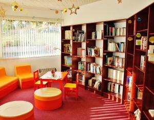 a library with a table and chairs and bookshelves at VVF Plaine d'Alsace Obernai Strasbourg in Obernai