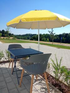 uma mesa azul, um guarda-chuva amarelo e duas cadeiras em Ferienwohnung Mundry 