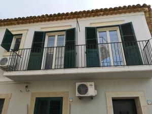 a building with green shutters and a balcony at Fichi e Gelsomino - Casa Vacanze in Donnalucata