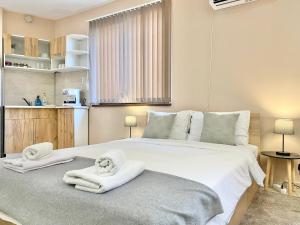 una camera da letto con un grande letto bianco con asciugamani di Studio for 4 Guests Next to Mall & Free Street Parking a Stara Zagora