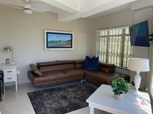 sala de estar con sofá marrón y mesa en Oceanway Self-catering Accommodation, en Gonubie