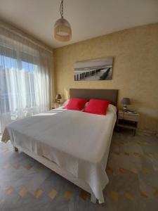 a bedroom with a large white bed with red pillows at Appartement Frejus Plage in Fréjus