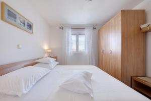 een slaapkamer met 2 witte bedden en een houten kast bij Apartment Justina in Murter