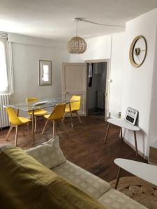 a living room with a table and yellow chairs at Tulle : superbe appartement quartier historique in Tulle
