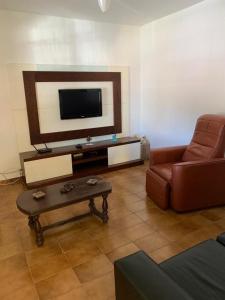 a living room with a couch and a flat screen tv at Casa Temporada Cabo Frio in São Pedro da Aldeia