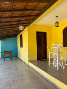 a room with a table and chairs and a yellow wall at Casa Temporada Cabo Frio in São Pedro da Aldeia