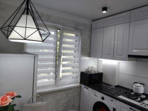 una cocina con armarios blancos y una ventana en Квартира однокомнатная VIP, en Uralsk