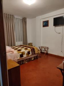 Un dormitorio con una cama y un televisor. en Suzet House, en Oxapampa
