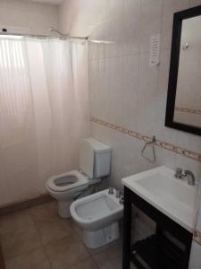 a white bathroom with a toilet and a sink at Complejo El Peregrino in Cortaderas
