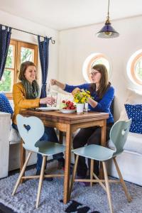 Due donne sedute a un tavolo in una stanza di WOHNWAGON Tiny Houses II a Gutenstein