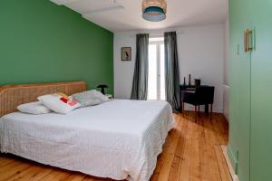 um quarto com uma cama branca e paredes verdes em Maison nichée au coeur des vignes proche de Givry em Givry
