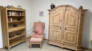 a room with a wooden cabinet and a chair at Ferienwohnung Panoramablick in Bolsterlang