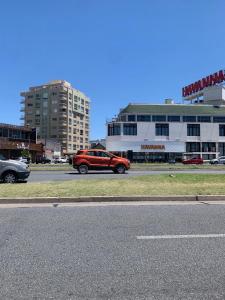 un coche rojo estacionado al lado de una calle en Departamento 2 Ambientes Nuevo La Perla en Mar del Plata