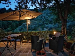 una mesa y sillas con una sombrilla en el patio en Agriturismo Tananei, en Marliana