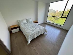 - une chambre avec un lit et une grande fenêtre dans l'établissement Cómodo Apartamento en Manizales, à Manizales