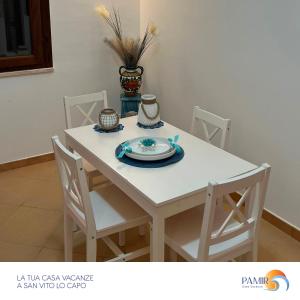 a white table with chairs and a plate on it at Pamir Casa Vacanze Villetta in San Vito lo Capo