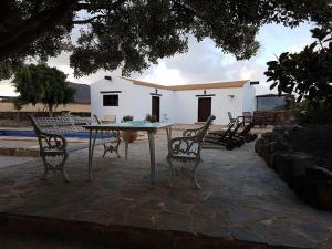 uma mesa e cadeiras em frente a um edifício em Casa Volcán em La Oliva