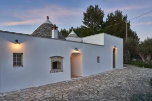 a white house with a stone driveway at Trulli OraziO in Monopoli