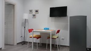 uma mesa com cadeiras e uma televisão na parede em Apartment Melograno5 em Catânia