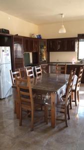 a kitchen with a wooden table with chairs and a refrigerator at Rosa Farm, Jerash Most Beautiful Villa in Jerash