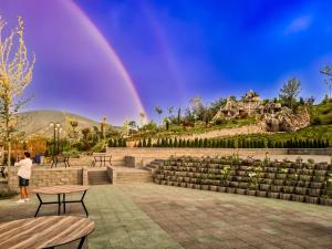 a rainbow in the sky over a park with benches at Verdisso Hotel & Restaurant in Demir Kapija